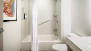 A modern bathroom with a bathtub, toilet, and a shower curtain.