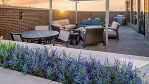 A rooftop patio with outdoor furniture, a grill, and a view of the sunset. - Hyatt House Auburn Hills / Detroit (Lake Orion)