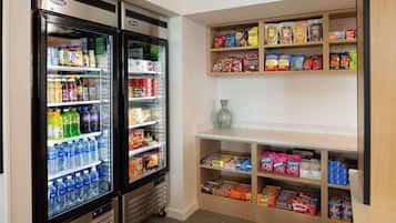 Un réfrigérateur à boissons, rempli de diverses boissons, et une étagère à collations contenant une variété d’aliments emballés.