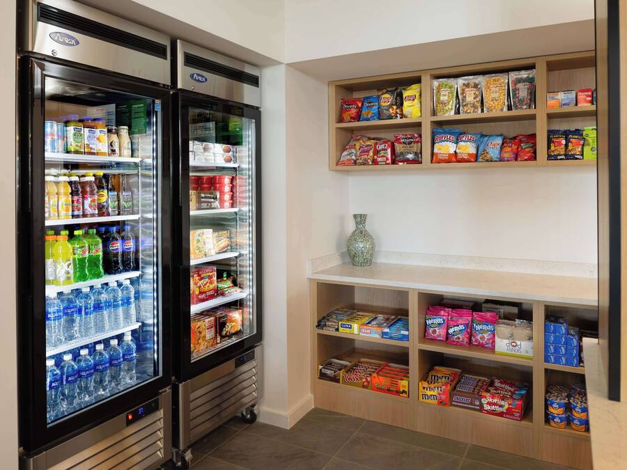 Un réfrigérateur à boissons, rempli de diverses boissons, et une étagère à collations contenant une variété d’aliments emballés.