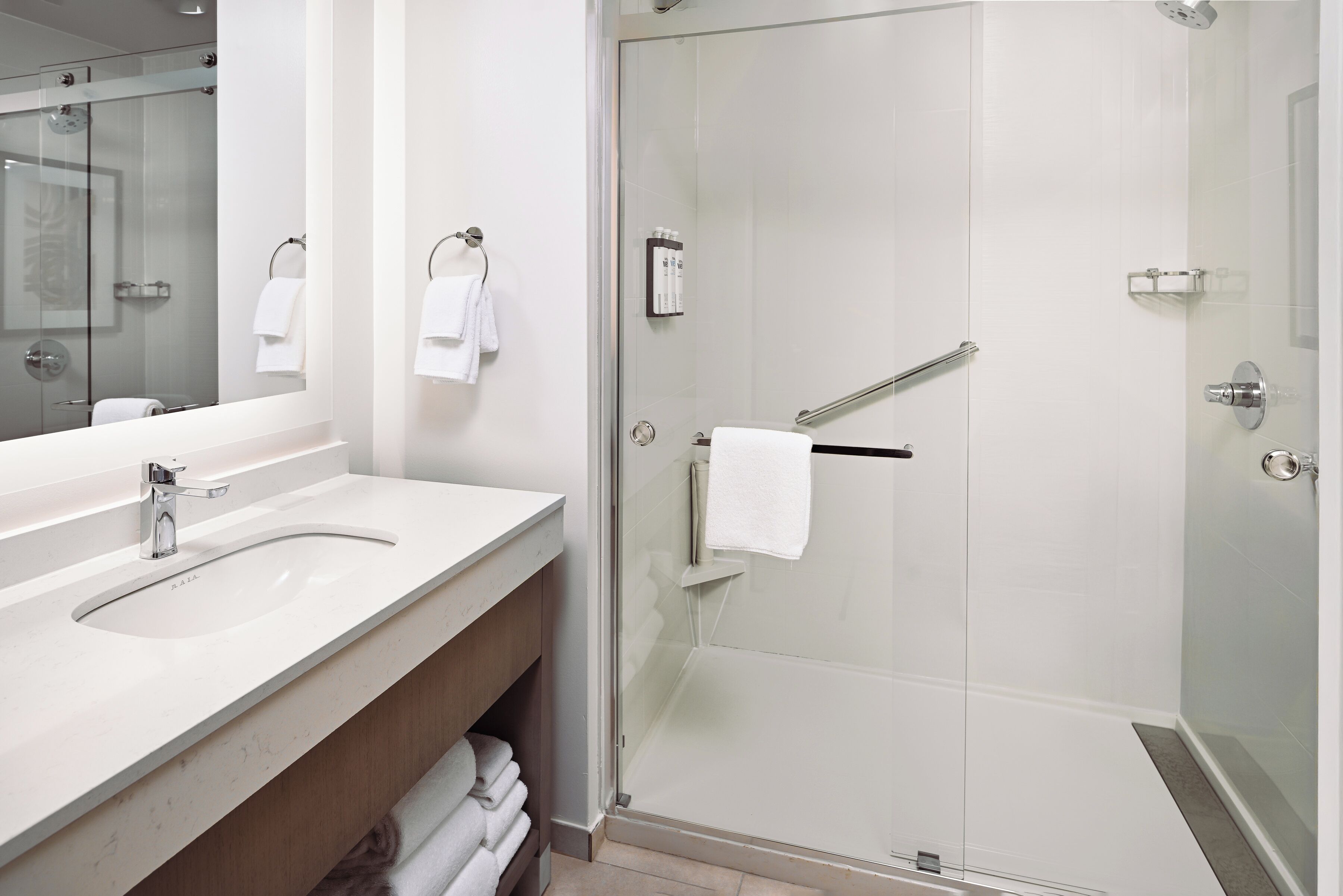 A modern bathroom with a glass-enclosed shower, a sink, and a mirror.