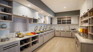 A modern kitchen with wooden cabinets, a breakfast bar, and various kitchen appliances. - Hyatt House Auburn Hills / Detroit (Lake Orion)