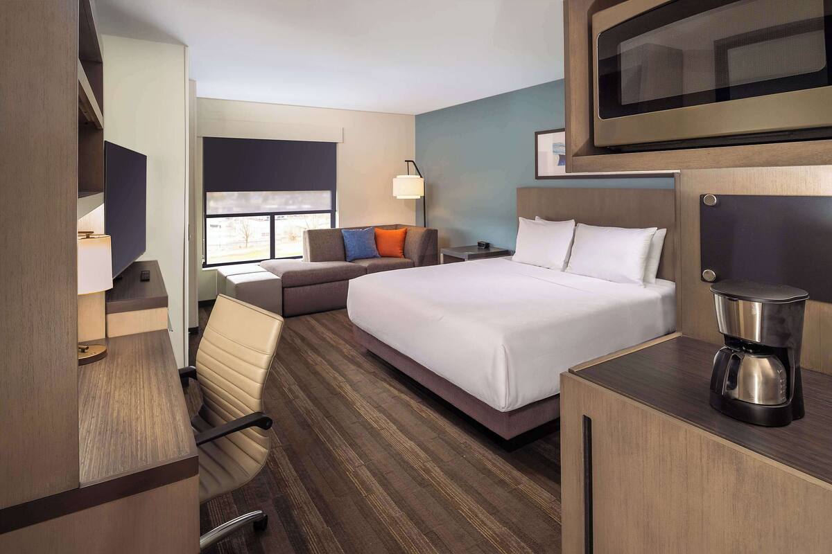 Een hotelkamer met een bed, een bureau, een stoel, een bank en een koffiezetapparaat.