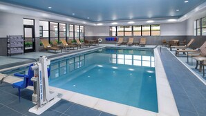An indoor swimming pool with clear water, surrounded by lounge chairs and tables, and large windows providing natural light. - Hyatt House Auburn Hills / Detroit (Lake Orion)
