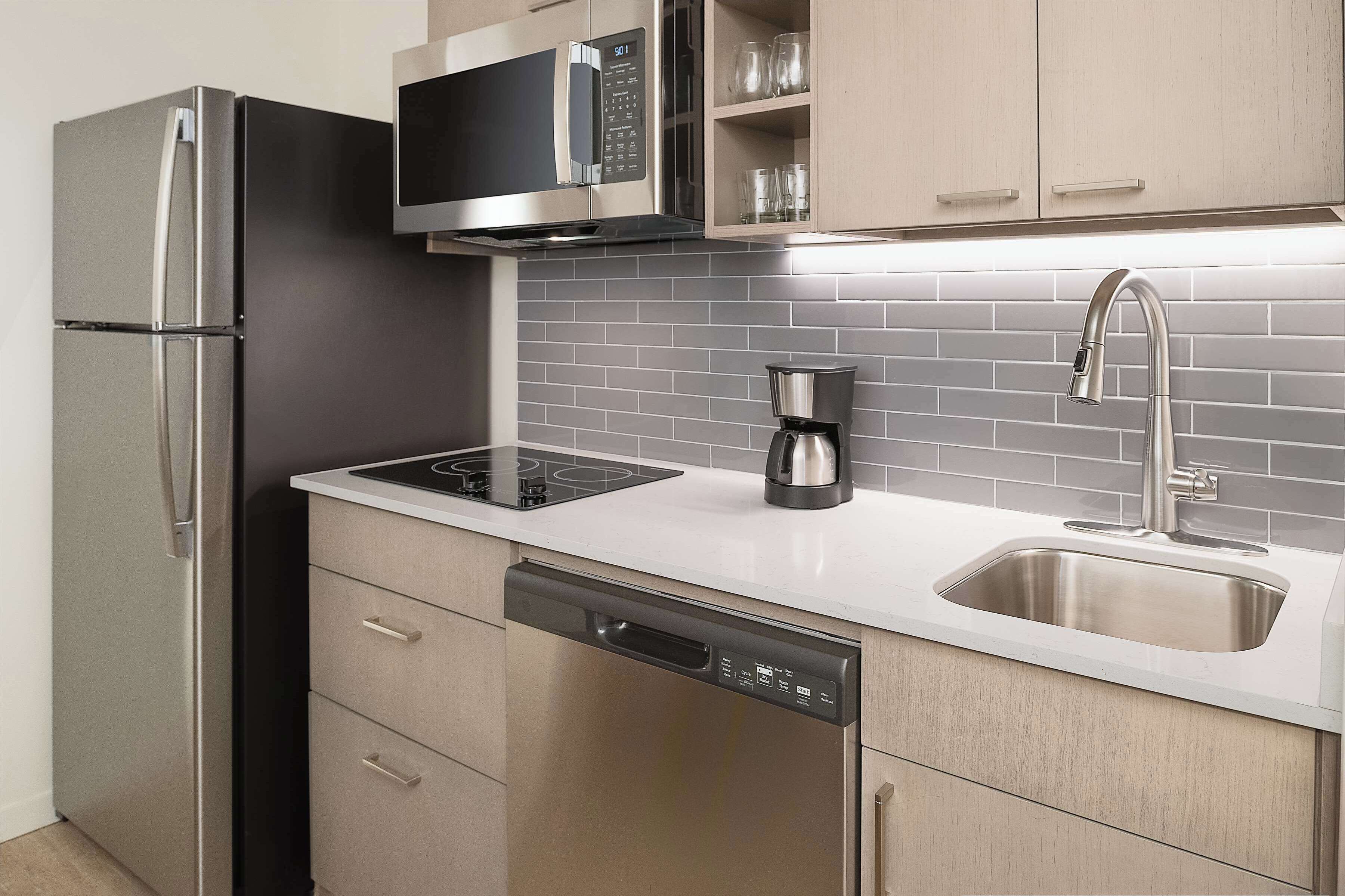 Una cocina moderna con electrodomésticos de acero inoxidable, lavavajillas y cafetera.