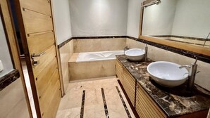 A bathroom with a bathtub, two sinks, and a wooden door. - Charming two bedroom apartment in the city center

 (Casablanca)