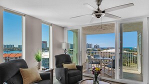Ein geräumiges Wohnzimmer mit großem Fenster, Deckenventilator und Balkon mit Sitzgelegenheit.