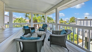 A covered outdoor deck with wicker furniture and a view of the surrounding area. - Destin-a-tion on the Water (Destin)