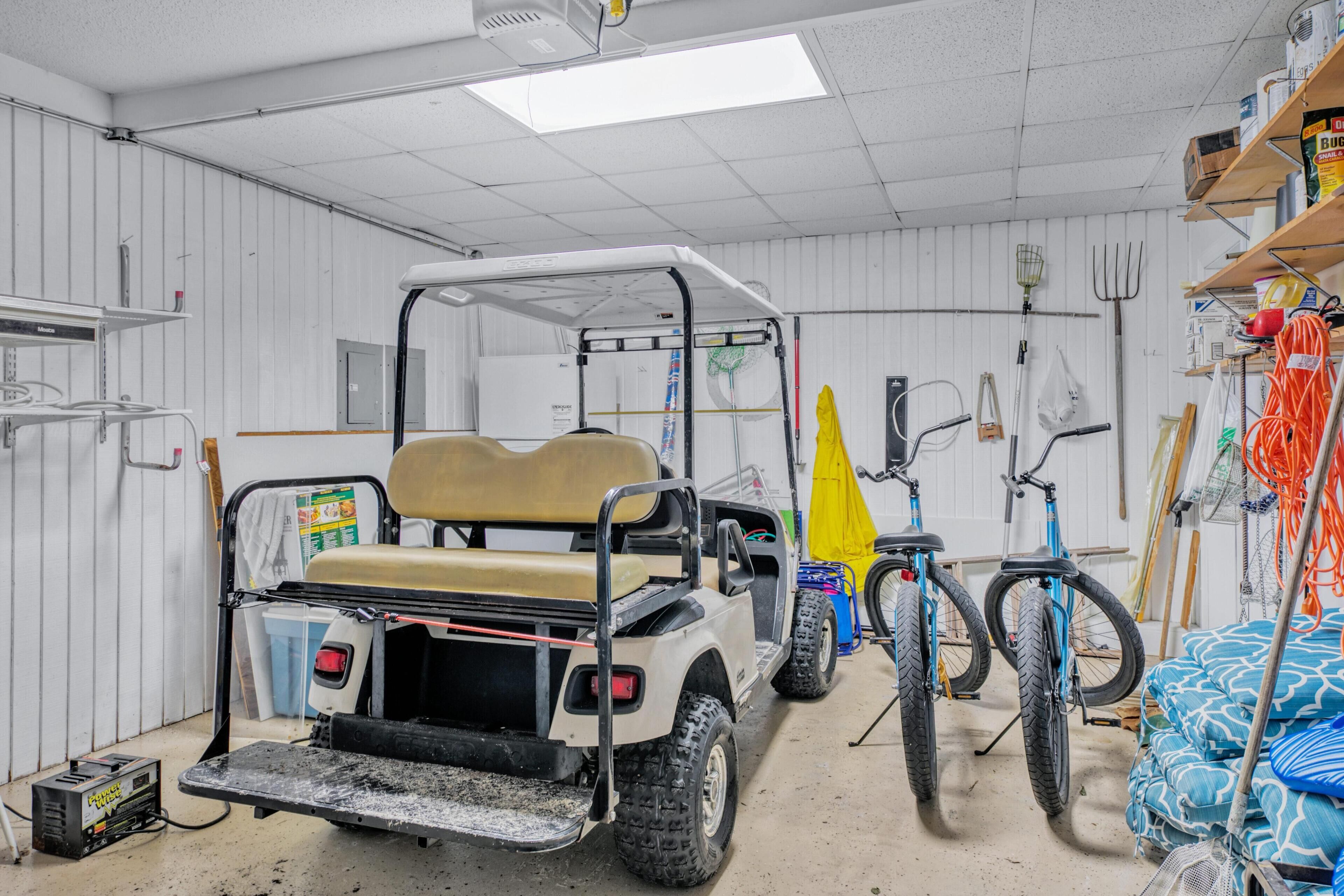A utility room with a golf cart, bicycles, and various tools and equipment.