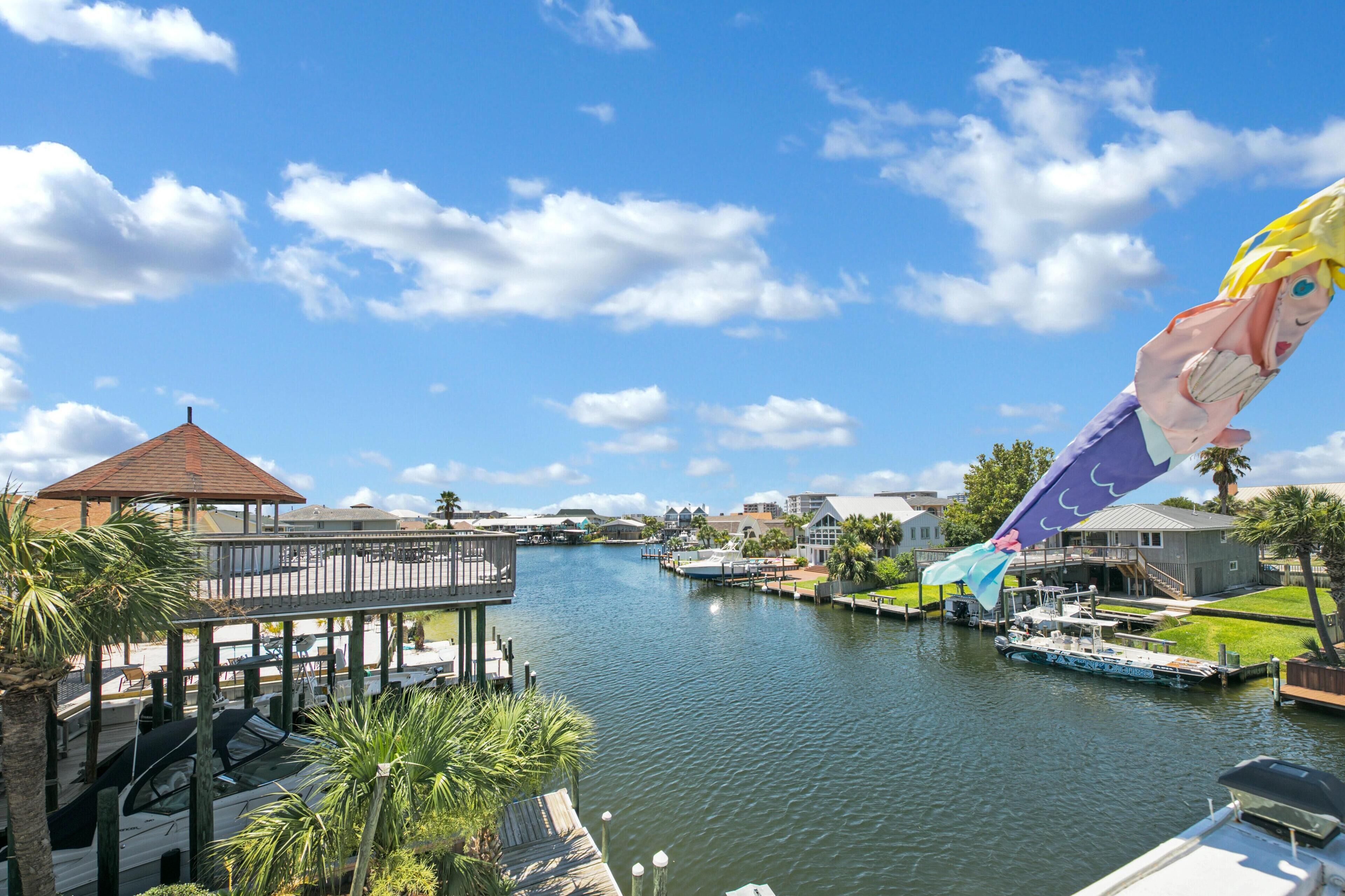 A riverside view with a gazebo, docked boats, and a pier.