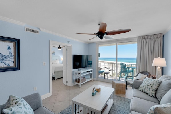 A living room with a TV, a ceiling fan, a sofa, a coffee table, and a balcony with a view of the ocean. - Destin on the Gulf 401 (Destin)
