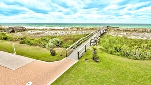 A beachside walkway leading to the ocean, with a wooden deck and a paved path. - Destin on the Gulf 401 (Destin)