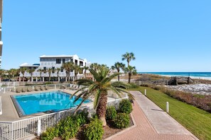 Une piscine entourée de palmiers, avec vue sur la plage.