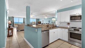 A modern kitchen with white cabinets, a granite countertop, and stainless steel appliances. - Destin on the Gulf 206 (Destin)