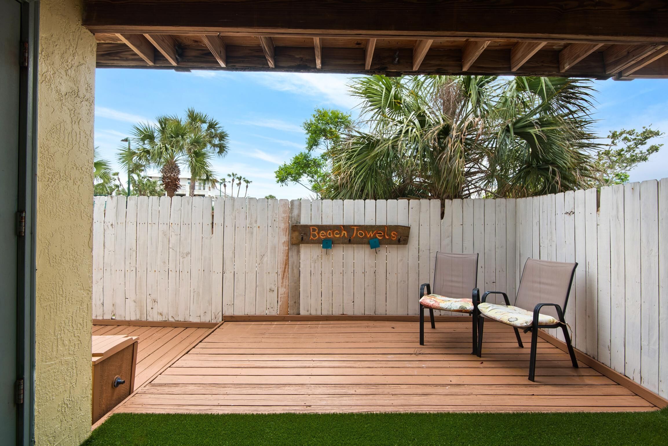 A wooden deck with two chairs and a sign that reads "Beach Towels."