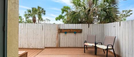 A wooden deck with two chairs and a sign that reads "Beach Towels."