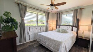 A bedroom with a bed, two bedside lamps, a ceiling fan, and a window with curtains.