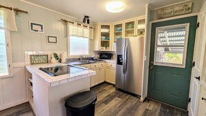 A compact kitchen with white cabinetry, a built-in microwave, and a stainless steel refrigerator.