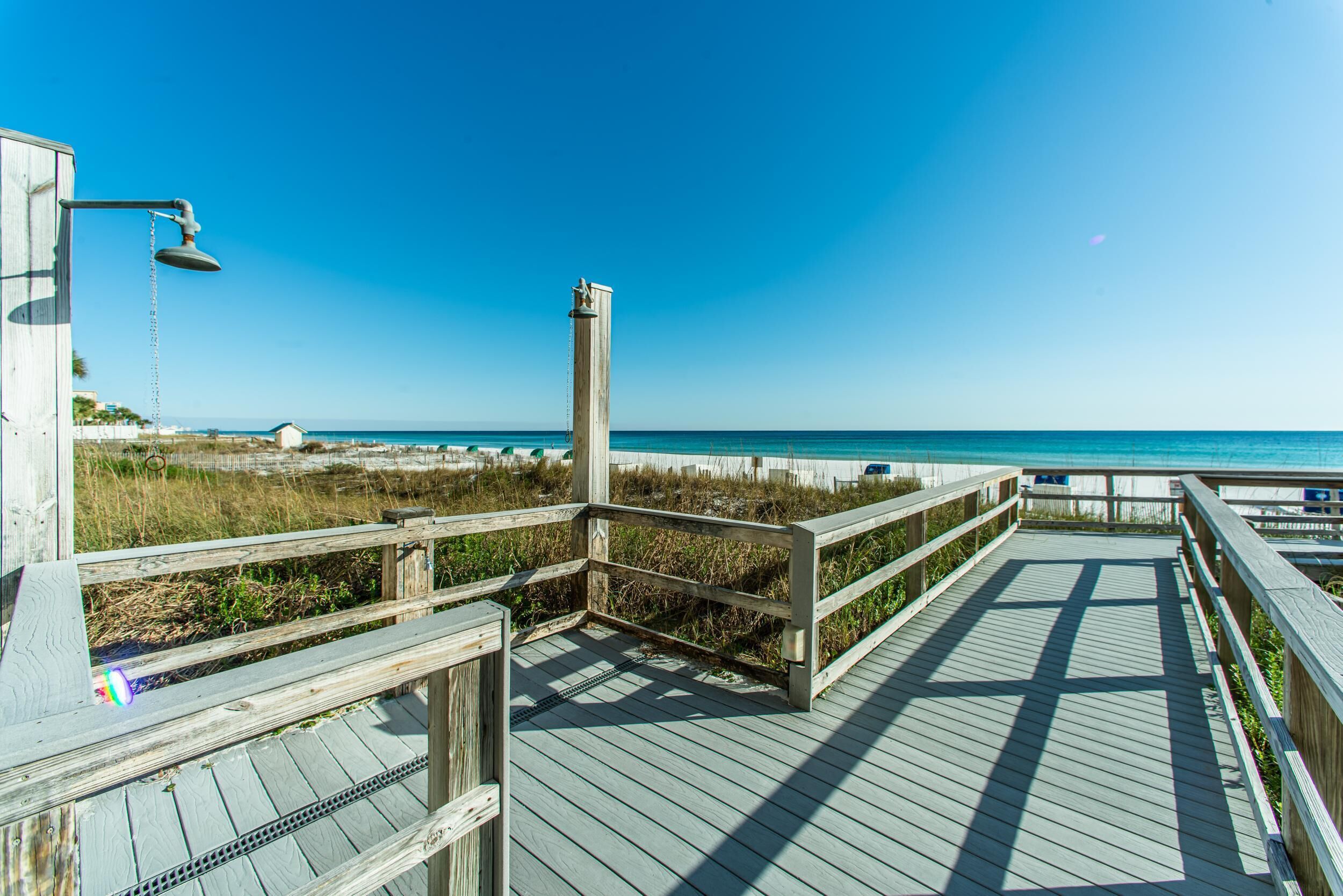 A wooden boardwalk leading to a beach with a clear view of the ocean.