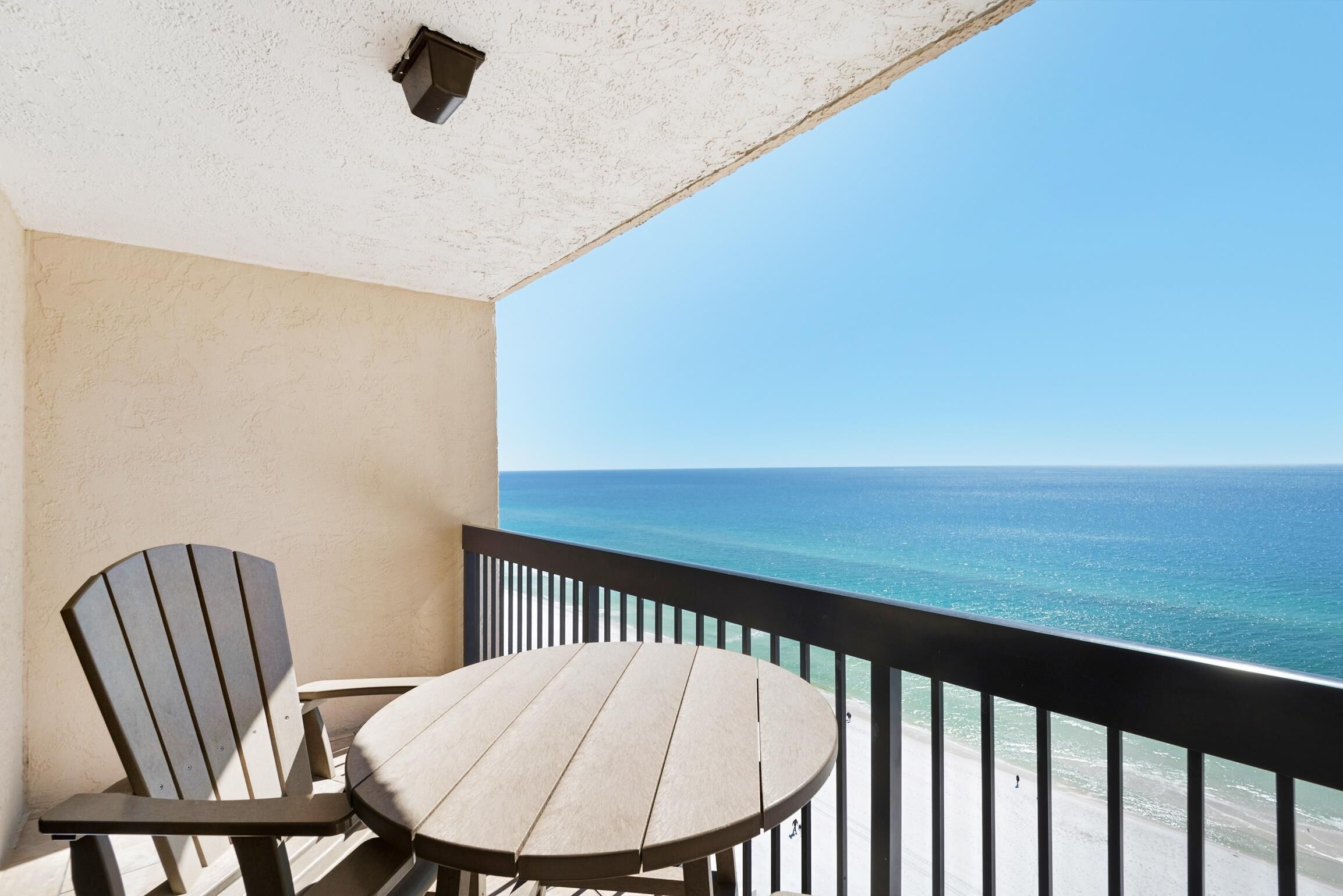 Ein Balkon mit Tisch und Stühlen mit Blick auf einen Strand und das Meer.