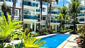 Un hotel moderno con piscina rodeada de palmeras y plantas tropicales.