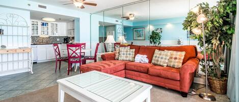 A living room with a red sofa, a white coffee table, and a dining area with red chairs.