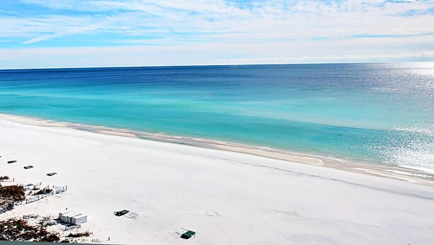 A beach with clear turquoise water, white sand, and a few structures in the distance. - Sundestin 1703 (Destin)