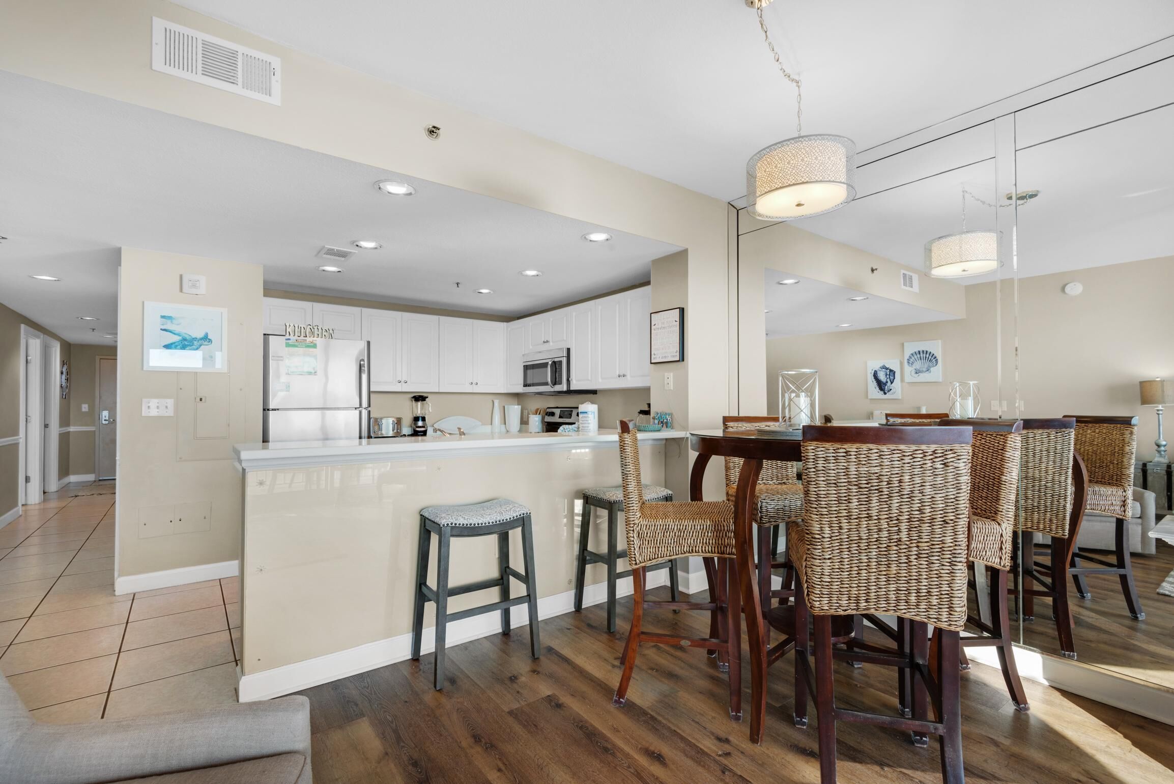 Une cuisine moderne avec des meubles blancs, un îlot central et un coin repas doté de chaises en osier.