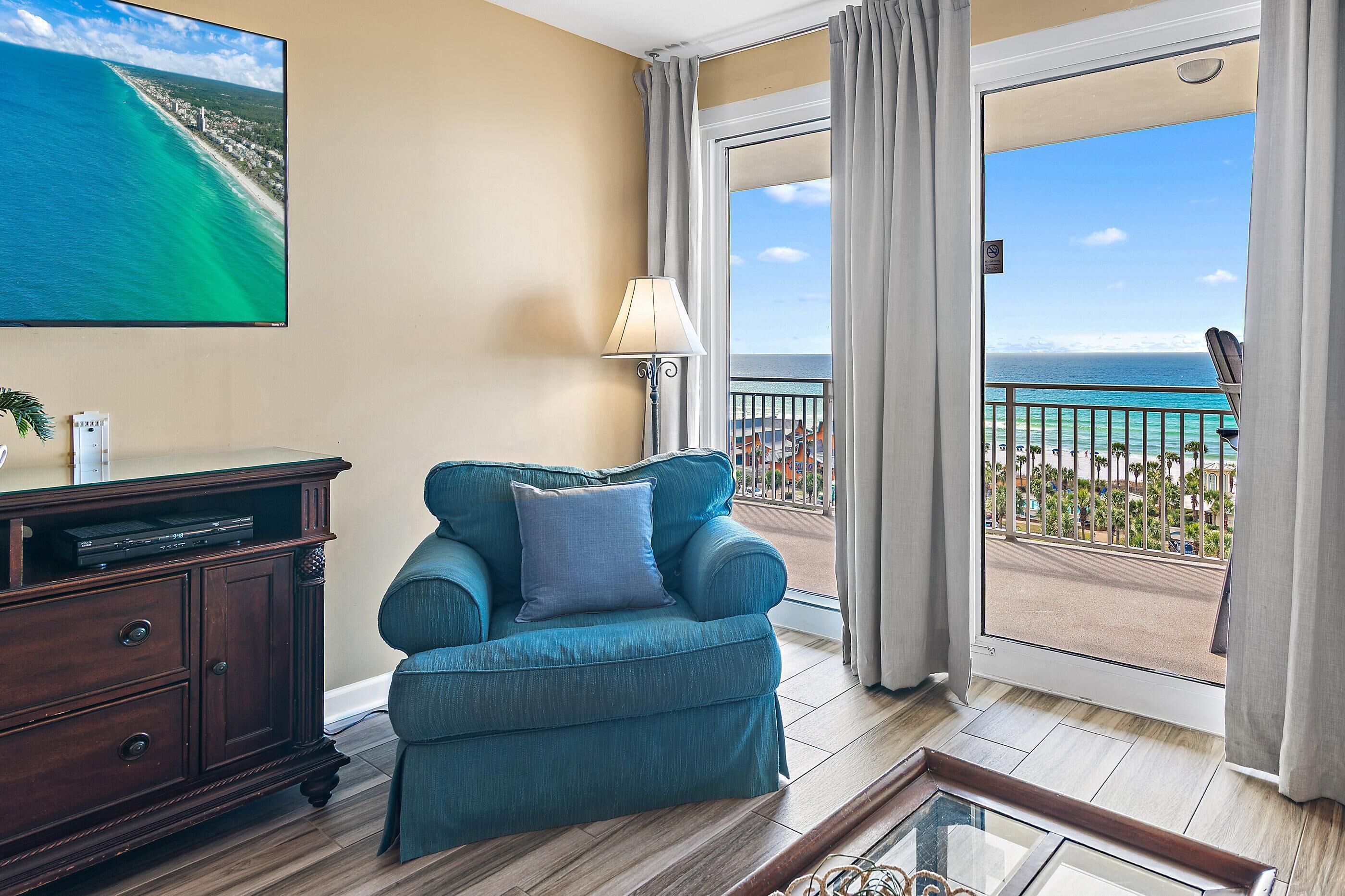 Une pièce comprenant un canapé, un téléviseur et un balcon avec vue sur l’océan.