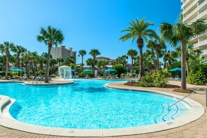 A swimming pool with palm trees, lounge chairs, and a fountain. - Sterling Shores 215 (Destin)