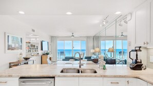 A modern kitchen with a large island, a built-in dishwasher, and a view of the ocean. - Sterling Sands 502 (Destin)