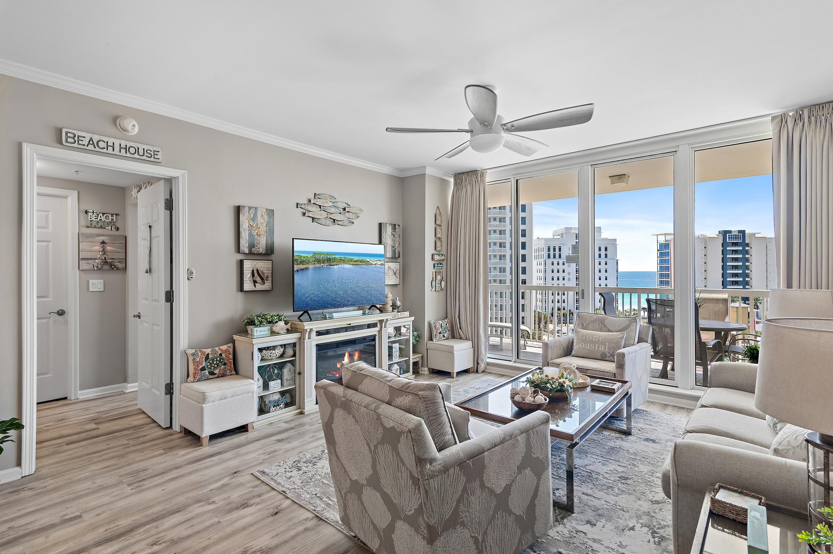 Amplio salón con televisor grande, asientos cómodos, chimenea y balcón con vista a la ciudad.