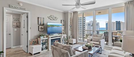 Amplio salón con televisor grande, asientos cómodos, chimenea y balcón con vista a la ciudad.