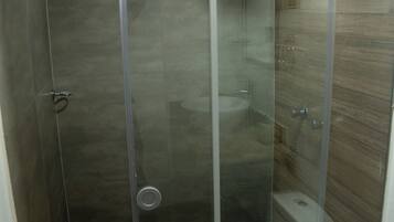 Een douchecabine met glazen wanden en een raam, een toilet en een wastafel.