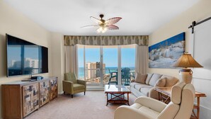 A modern living room with a large flat-screen TV, a sofa, a coffee table, and a view of the ocean. - St. Lucia 1002 (Destin)