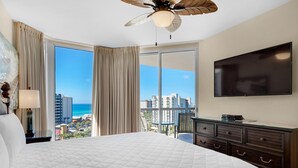 A hotel room with a large bed, a ceiling fan, a TV, and a balcony with a city view. - St. Lucia 1002 (Destin)