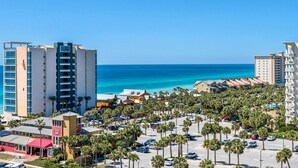 A coastal hotel with multiple high-rise buildings, a parking lot, and palm trees. - St. Lucia 1002 (Destin)