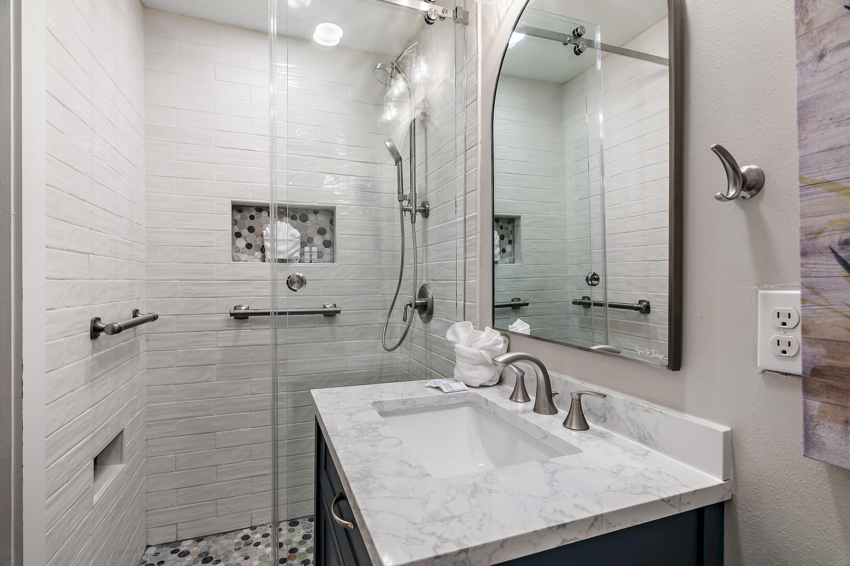 A modern bathroom with a glass-enclosed shower, a marble sink, and a large mirror.