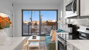 A modern kitchen with a large window, a sofa, and a dining area.