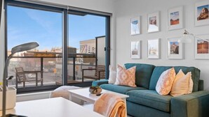 A modern living room with a green sofa, a white coffee table, and a large window overlooking a cityscape.