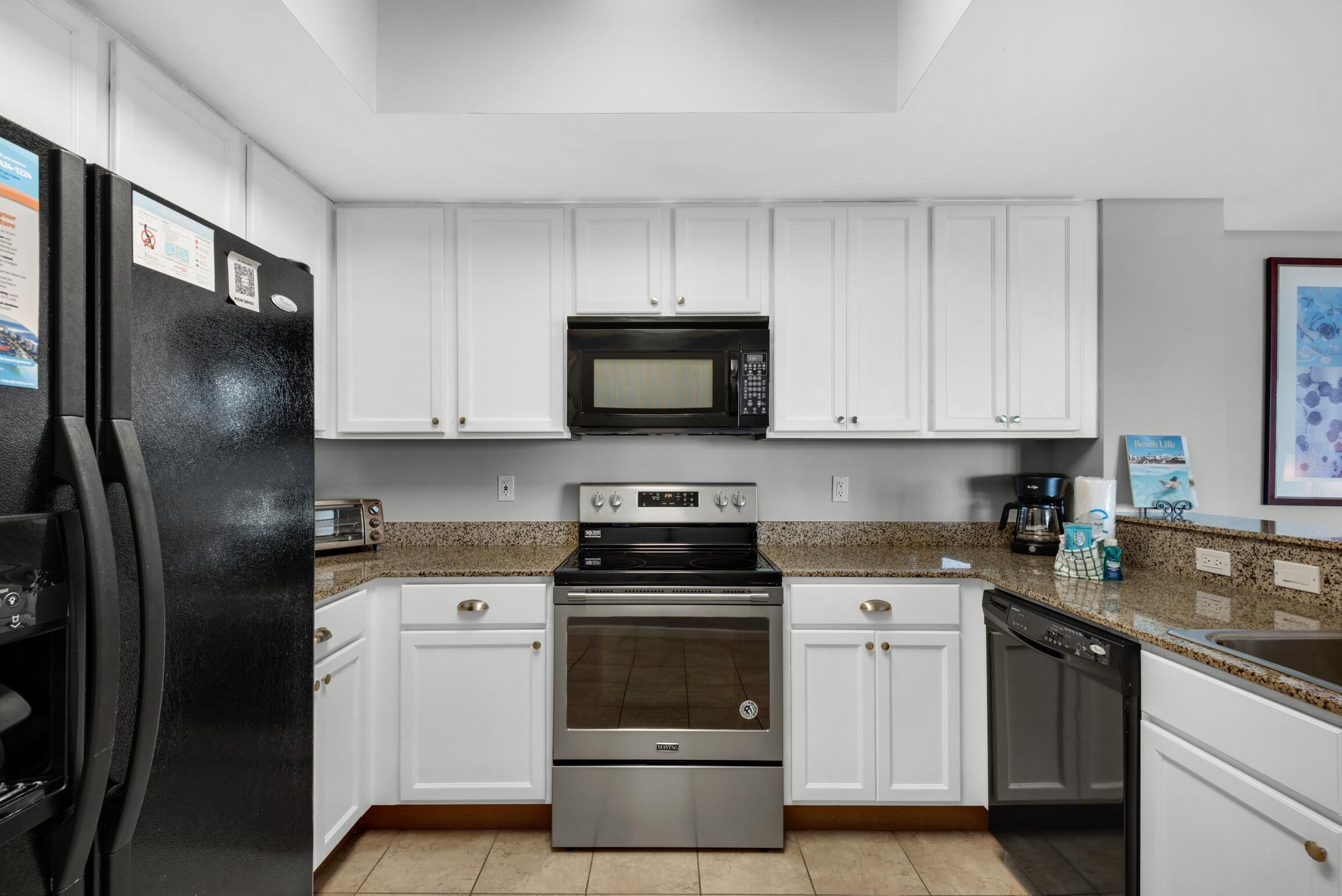 A kitchen with white cabinets, a black refrigerator, a microwave, an oven, and a dishwasher.