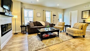 A living room with a fireplace, a sofa, a coffee table, and a patterned armchair.