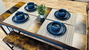 A dining table with four blue bowls and saucers, a small potted plant, and a wooden floor.