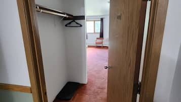 Un pasillo con una puerta de madera, un perchero y suelo alfombrado.