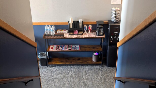 A staircase leading to a room with a coffee machine, water bottles, and a shelf with photos. - The Hibernation Station (Sterling)