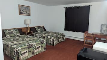 A room with two beds, a desk, a chair, a lamp, a picture on the wall, and a window with curtains.