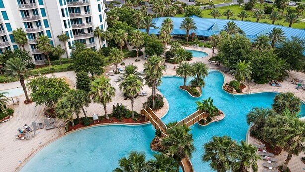 A resort with multiple swimming pools surrounded by palm trees and lounge areas.