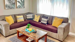 Una sala de estar con un sofá modular, una mesa de centro y dos cuadros colgados en la pared.