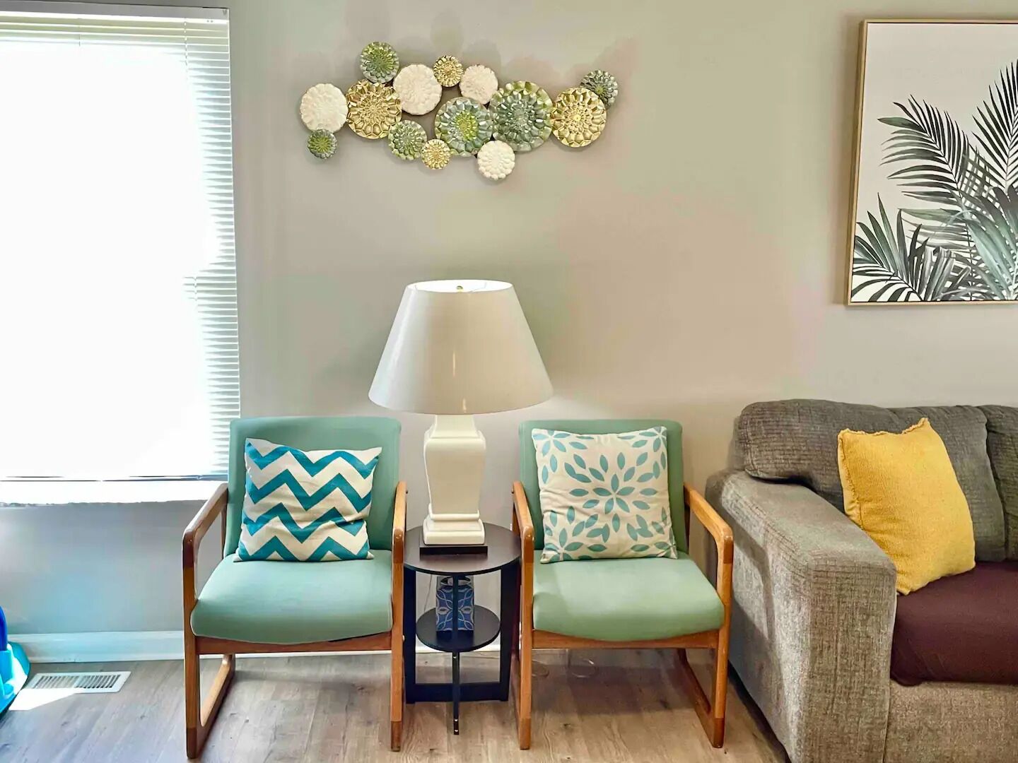A living room with two armchairs, a side table, a lamp, and a couch.