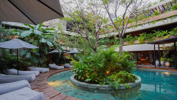 A pool area with a wooden deck, lounge chairs, and potted plants.